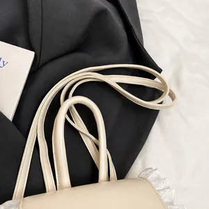 Detail view of the adjustable slim leather straps on this elegant beige shoulder bag
