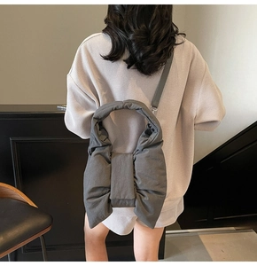 Detail view of large grey fabric bow shoulder bag with padded texture and soft strap