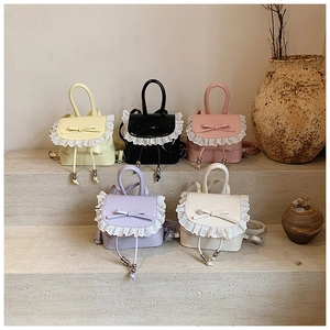 Detailed view of mini lace-trimmed bow backpacks in multiple pastel colors on steps