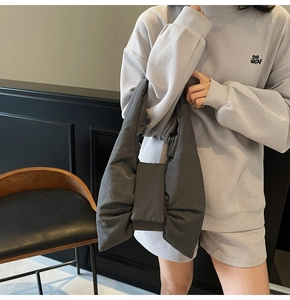 Detail shot of a dark gray bow-shaped tote bag in nylon fabric on a shoulder model