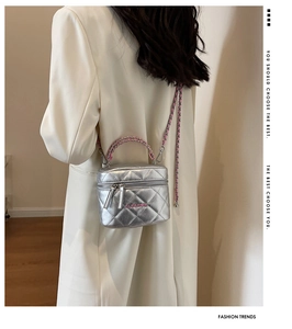 Dettaglio della borsa a scatola argento con catena rosa e logo Clear su blazer bianco