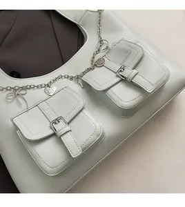 Detailed close-up of light green tote bag with pockets, silver buckle, and heart chain charm