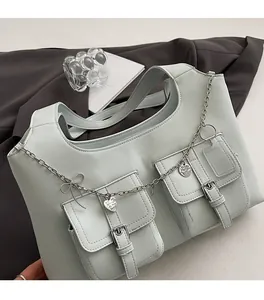 Detail of mint green faux leather tote bag with functional pockets and silver chain charms