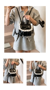 Detalle de mini mochila de charol negro con encaje blanco y lazo decorativo negro