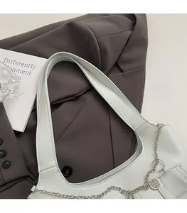 Close-up of minimalist white shoulder bag with silver metal chain and comfortable wide strap