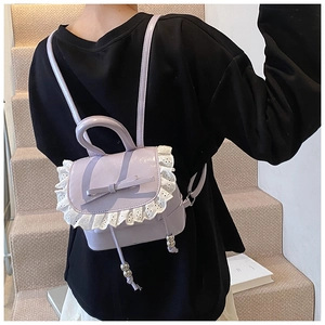 Detail of light purple patent leather backpack with lace trim and bow on model