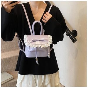 Detalle de mini mochila lavanda con encaje blanco y decoración de lazo en la parte frontal