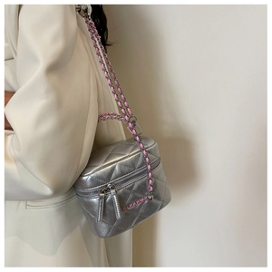 Detail of silver quilted box bag with pink chain strap and heart logo on white blazer