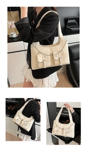 Detail of cream faux leather tote with twin flap pockets and silver heart chain charm