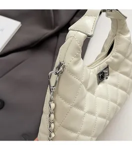 Détail de la texture cuir matelassé et du fermoir rotatif argenté du sac crème