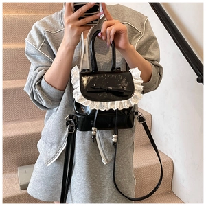 Detail of a black faux leather balletcore backpack with lace trim and bow accent