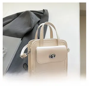 Dettaglio borsa in ecopelle bianco crema con chiusura rotante in argento e manico