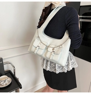 Detail of light mint tote bag with double front pockets and metal charm chain