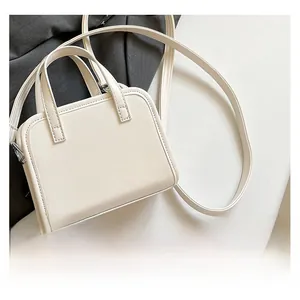 Dettaglio di una borsa a mano bianca quadrata minimalista in ecopelle liscia con doppi manici