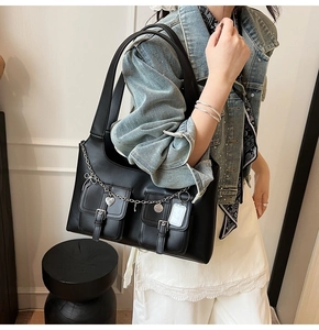 Detail of black faux leather tote featuring silver chains and heart charms decoration