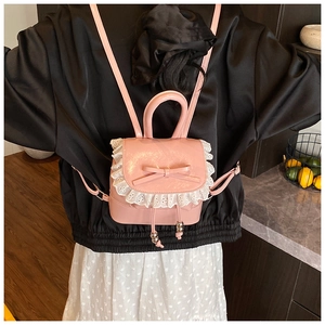 Vista detallada de la mini mochila de cuero rosa con lazo y ribete de encaje blanco suave