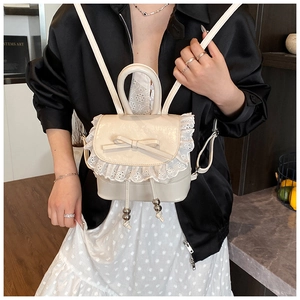 Detail of cream white mini backpack with delicate lace trim and ribbon bow decoration