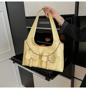 Detailed view of pale yellow tote bag with silver chain and decorative pockets