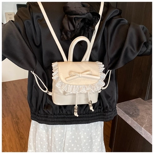 Detalle de mini mochila crema con adorno de lazo y borde de encaje blanco suave