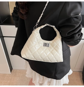 Borsa trapuntata bianca con chiusura a scatto argento e tracolla metallica indossata