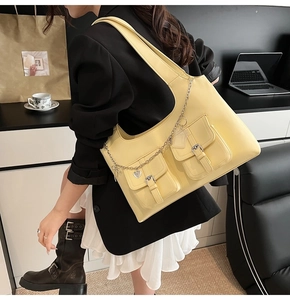 Detail of yellow PU leather tote bag with silver heart chain and flap pockets on casual outfit