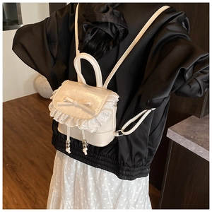 Detail of a creamy white mini backpack with delicate lace trim and a bow accent on the back