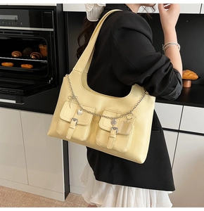 Detail of cream shoulder bag featuring double flap pockets and silver heart chain detail