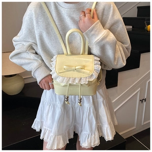 Detalle de la mini mochila amarillo crema con bordado de encaje y lazo en cuero brillante