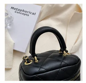 Detail of black quilted leather handbag with thick top handle and golden hardware