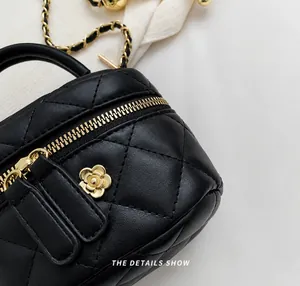 Detail of quilted leather bag featuring a gold camellia flower zipper and chain strap