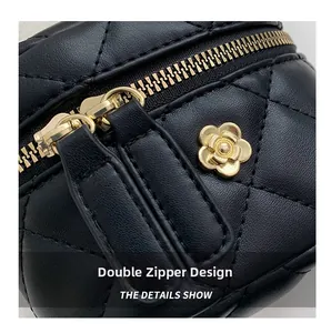 Detail of black quilted leather bag with dual gold zippers and camellia metal charm