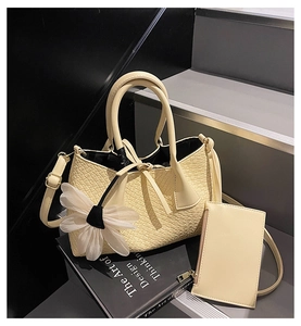 Detail showing cream woven bucket bag set with white flower charm and inner pouch