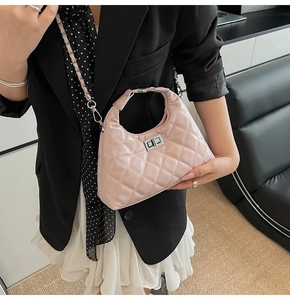 Dettaglio della borsa hobo trapuntata rosa chiaro con chiusura girevole su un blazer