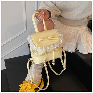 Detail of cream-colored ballet-style backpack featuring delicate lace trim and bow accent