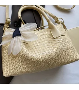 Detail of beige woven bucket bag showing intricate cross-weave texture and flower charm