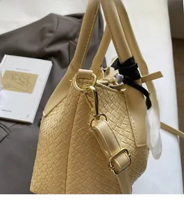 Detail view of woven leather bucket bag texture with polished light gold metal hardware hooks