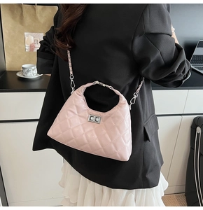 Sac bandoulière matelassé rose avec chaîne argentée dans un bureau moderne chic