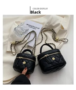 Close-up of black mini quilted box bag with chain strap and gold floral hardware detail