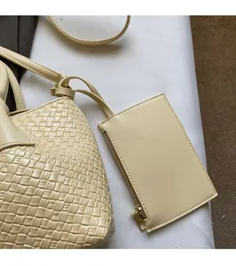 Close-up of woven cream tote bag with matching zippered pouch and golden hardware detail