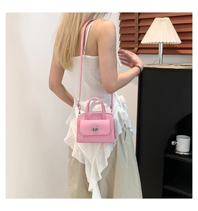 Detail of pink PU leather handbag showing silver turn-lock clasp and double handles