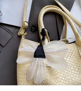 Detail of creative white petal bag charm with black center on a yellow woven handle