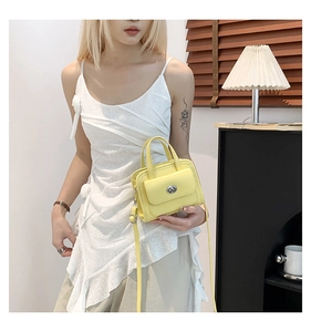 Borsa a mano mini gialla con chiusura a rotazione argento mostrata in un ambiente interno