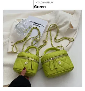 Close-up of green quilted box bags with floral zipper charms and chain straps