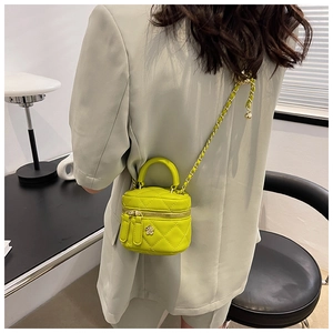 Detail of lime green quilted mini crossbody bag with gold floral clasp on green blazer