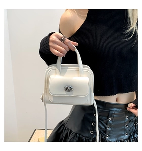 Chic beige PU leather handbag with metal twist lock shown in a lifestyle fashion shot