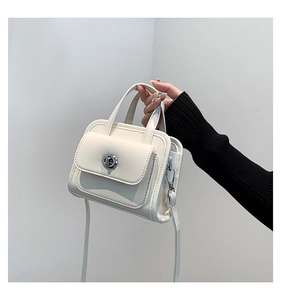 Detail of white mini briefcase bag with silver twist lock and smooth leather texture