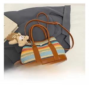 Detailed view of colorful woven bucket bag with brown leather straps and cute bear charm