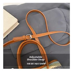 Detail of adjustable brown leather strap with silver buckle on contrast woven bucket bag