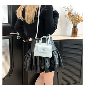 Dettaglio di una borsa quadrata in pelle blu menta con chiusura a rotazione in metallo