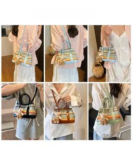 Detailed view of striped straw woven crossbody bag with cute teddy bear charm